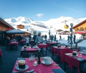 A panoramic, photorealistic winter scene of a bustling ski resort in the German Alps, shot in 16:9 format. In the foreground, a neatly set outdoor dining terrace of a mountain restaurant features empty tables with red-checkered cloths, steaming coffee cups, and lit candles, suggesting a peak season atmosphere. The background shows snow-covered slopes, a ski lift, and guests in winter gear arriving and departing. The lighting is soft natural daylight with clear blue sky, emphasizing a dynamic yet inviting hospitality environment. No text, logos, or visible faces are present. The image conveys the high demand for service staff in seasonal tourism.